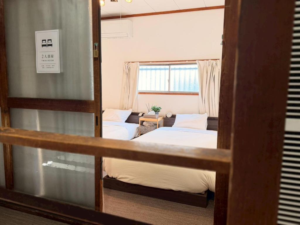 a room with two beds and a window at ura San Jose ツインルーム in Okayama