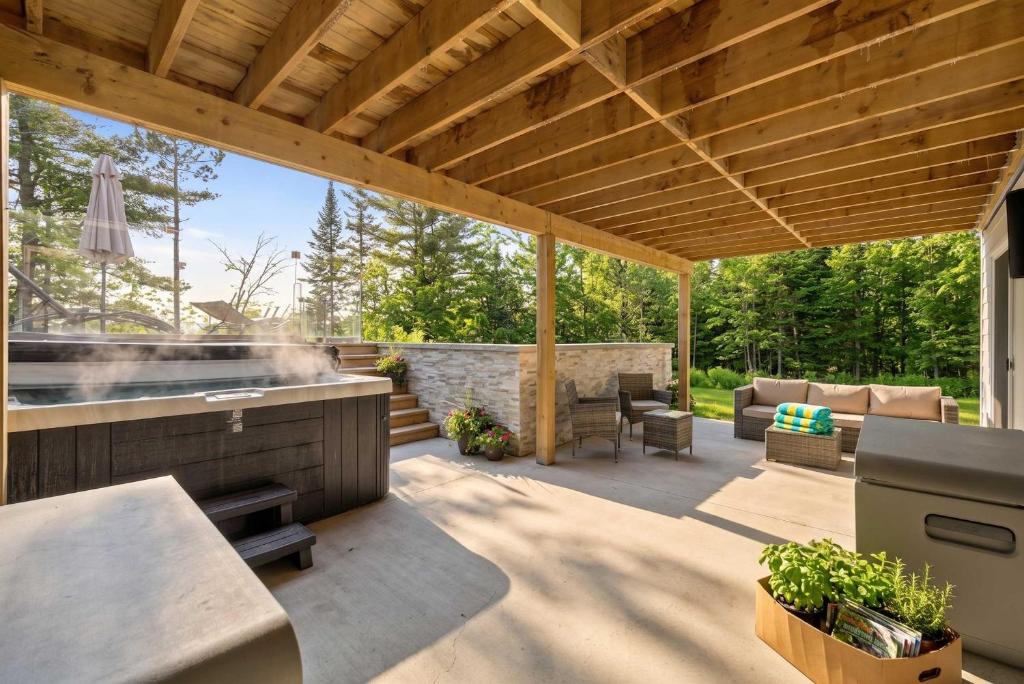 a covered patio with a grill and a table at Spa Pool Table - Luxurious pool - Chalet Houefifa in Saint Come