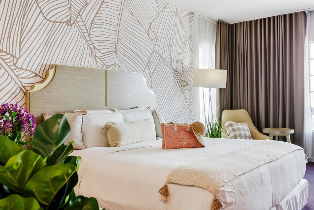a bedroom with a large white bed and a chair at Alamo Hotel in Miami Beach