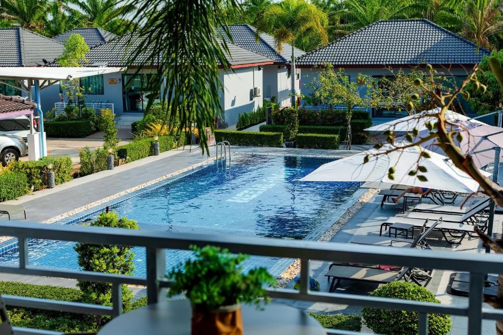 a swimming pool with an umbrella and chairs at Neenlawat Riverside in Suratthani