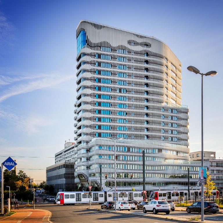 a tall building with cars parked in a parking lot at The Zipper Hotel und Apartments in Düsseldorf