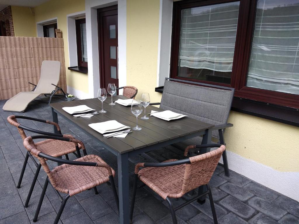 a black table with chairs and wine glasses on a patio at Helena Ferienwohnung in Hemfurth-Edersee