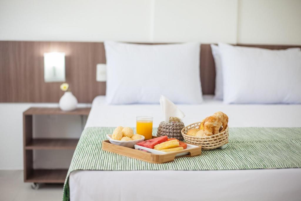 a tray of food and drinks on a bed at João Pessoa Hplus Beach in João Pessoa