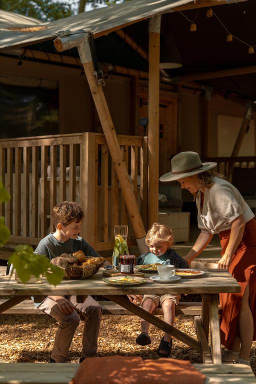 a woman and two children sitting at a picnic table at Gooise Heide in Huizen