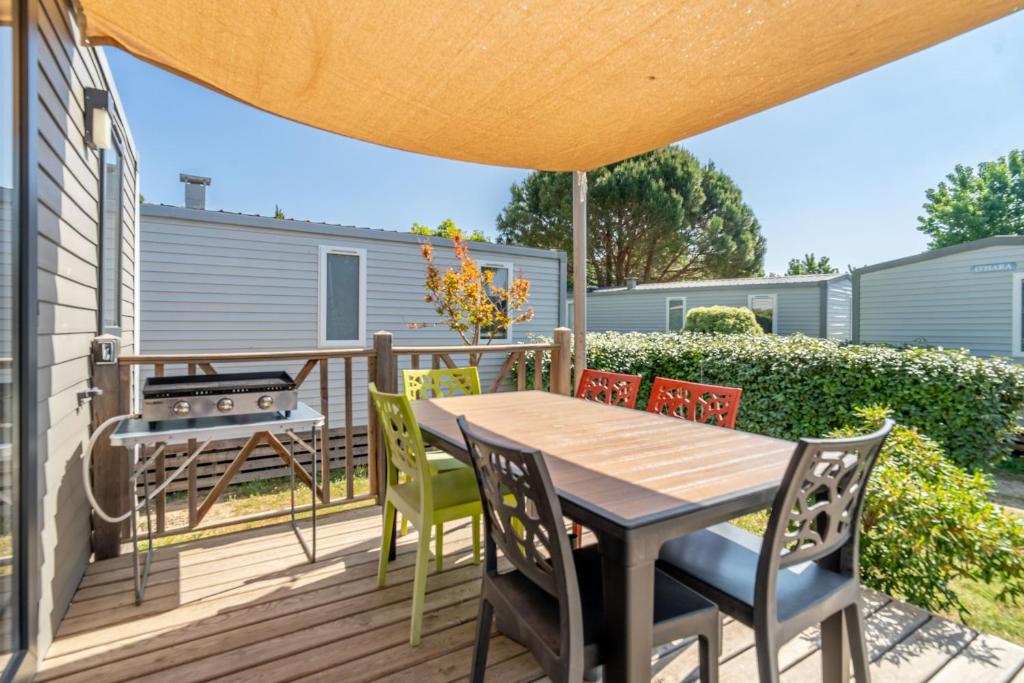 a deck with a table and chairs and a grill at Camping Valras plage 5 étoiles in Vendres