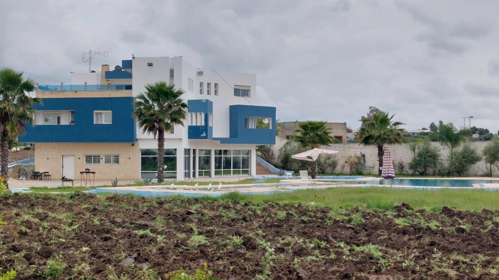 a building with a swimming pool and palm trees at Chambres d'hôtes - Écohâme - Guitar Palace in Ouazzane