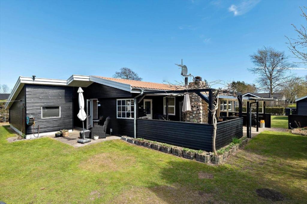 a small black house with a grass yard at OH585-Hadsund-Brondbaekken-34 in Øster Hurup