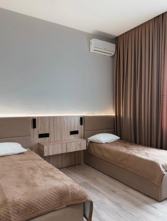 a hotel room with two beds and a window at Small Cozy Spa Hotel in Aktobe