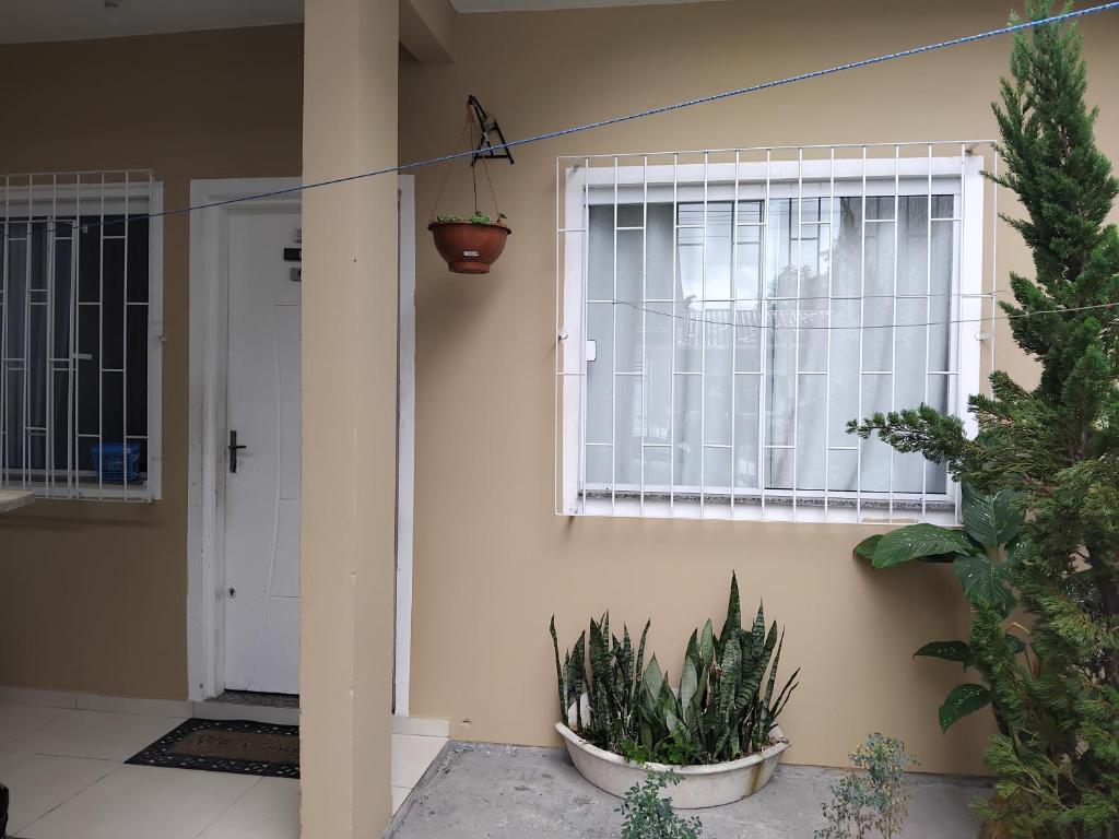 a front door of a house with a window and plants at EM CASA in Palhoça
