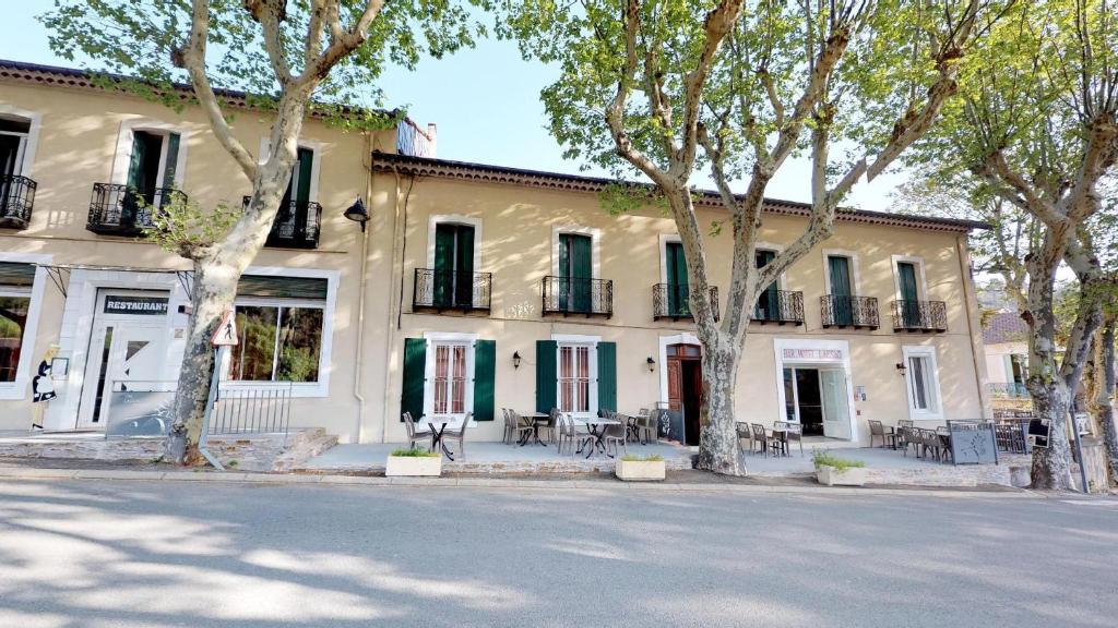 a building with trees in front of a street at Hotel restaurant LAISSAC SPEISER in Olargues