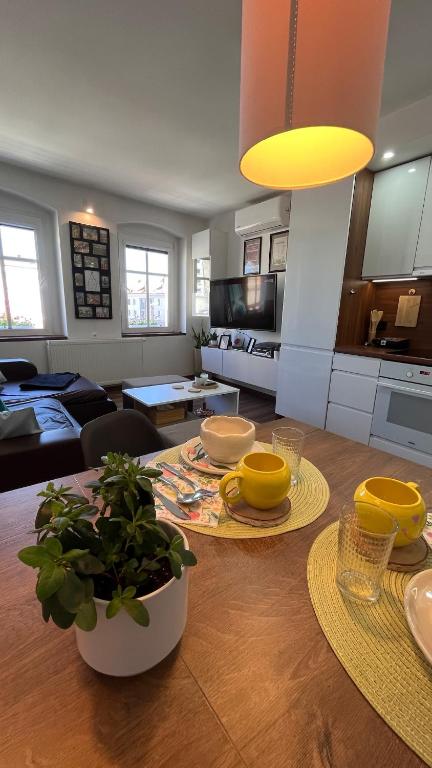 a kitchen and living room with a wooden table with yellow dishes at Apartament Crooked stairs in Zielona Góra