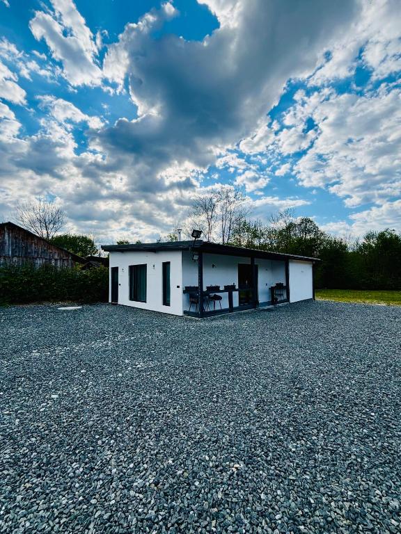 a small white house on a gravel lot at Casuta cu ciubar Valea Avrigului - Secret Forest in Avrig