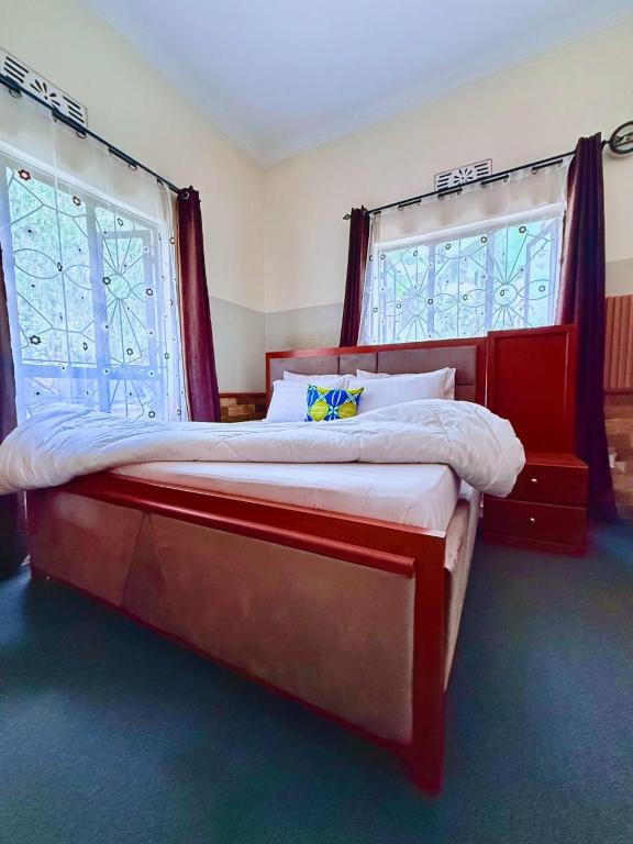a large bed in a room with two windows at Eva Residence Arusha in Arusha