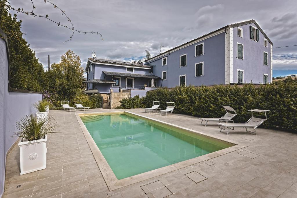 a swimming pool with chairs and a house at CuorNice - LG Estate in Ripe San Ginesio
