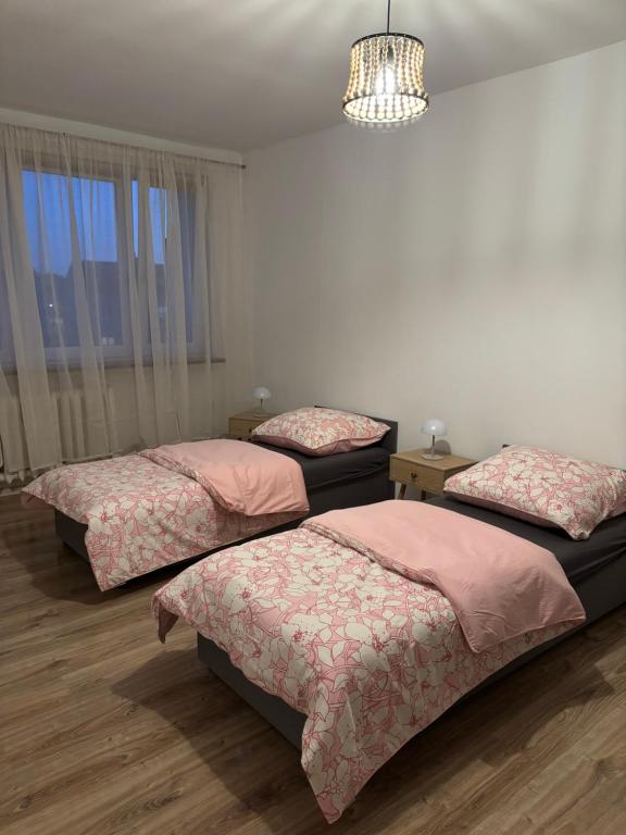 a bedroom with three beds and a chandelier at Mieszkanie BLOK in Złotów