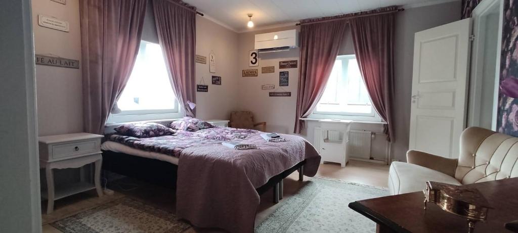 a bedroom with a bed and two windows at Nummen Goto, kivenheitto torilta in Rauma