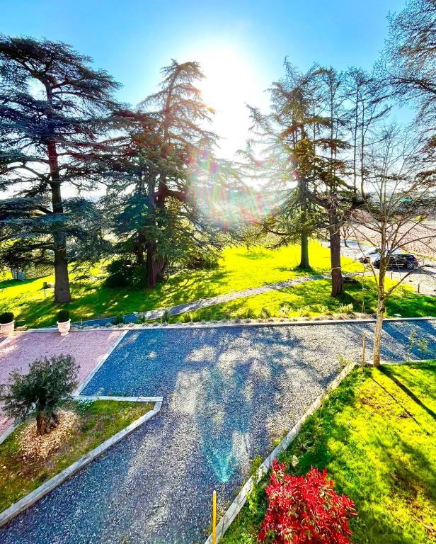 an empty road in a park with trees and grass at Gîte Les Cèdres in Pommiers