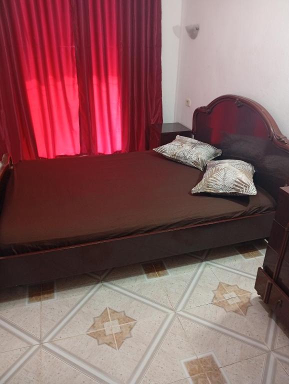 a bed in a room with a red curtain at Maison centre in Tazarka