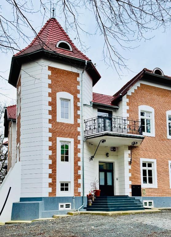 a brick and white house with a balcony at Sándor János Villa in Sovata