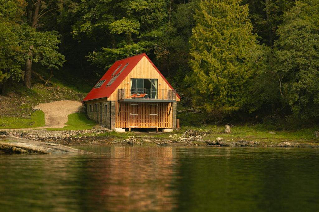 a house with a red roof next to a body of water at Sail Loft in Acharacle