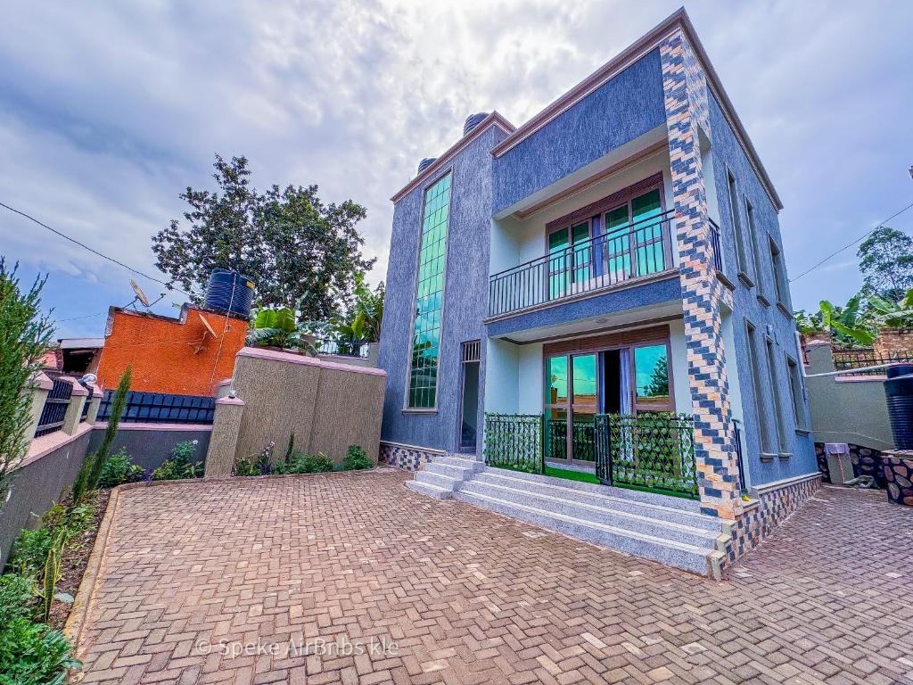 a blue building with a balcony on a brick driveway at Speke homes full apartment!!! in Kabale