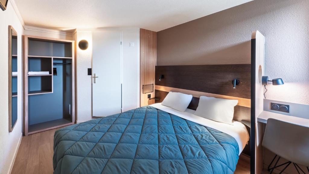 a hotel room with a blue bed and a chair at Premiere Classe Lyon Ouest - Tassin in Tassin-la-Demi-Lune