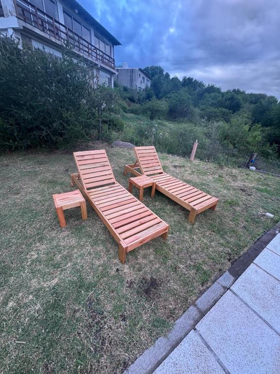 two wooden benches sitting in the grass near a building at Casa Mirador del Lago in Villa Parque Siquiman