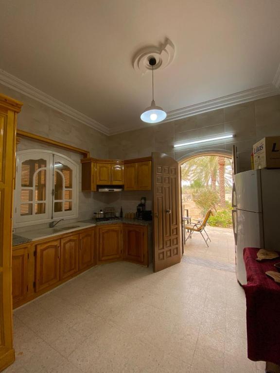 a kitchen with wooden cabinets and an open door at Dar hania in Tozeur