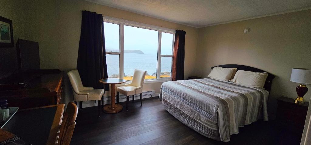 a hotel room with a bed and a large window at St Ann's Motel & Cottage in Baddeck
