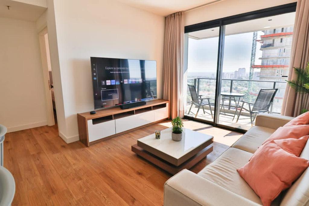 a living room with a couch and a tv and a table at Steps from the Shopping del Sol! in Asunción