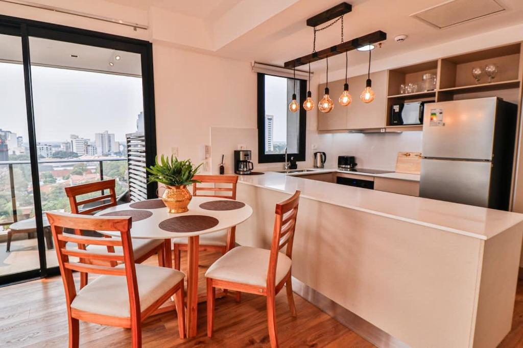 a kitchen with a table and chairs and a refrigerator at Large Apartment Just Steps from Shopping del Sol in Asunción