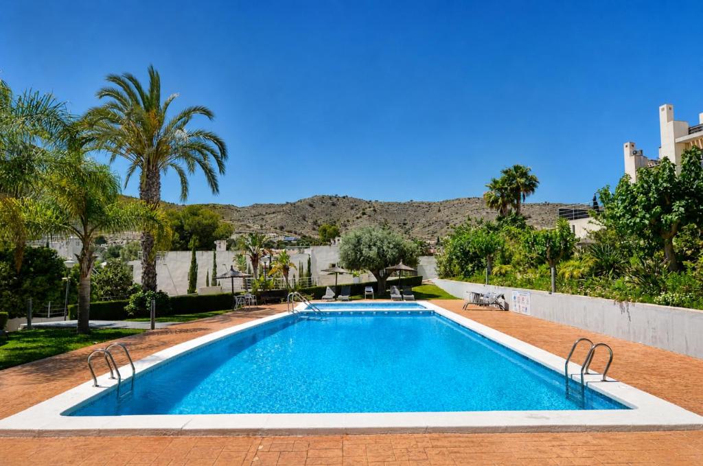 a swimming pool in a yard with palm trees at Exquisite Costa Blanca Escape Townhouses in El Campello
