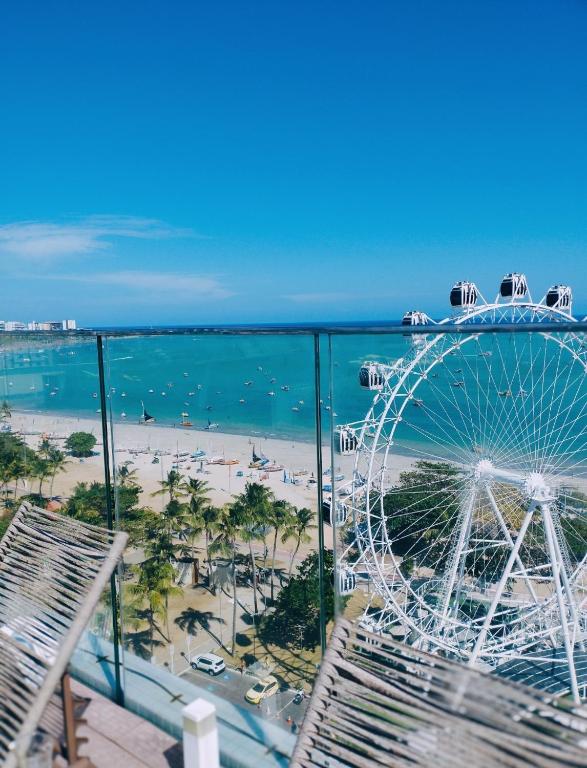 a ferris wheel next to a beach and the ocean at Pajuçara Front Beach in Maceió