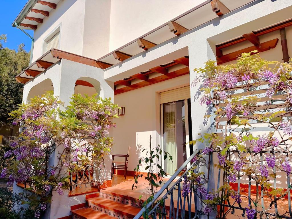 a white house with purple flowers on the stairs at Villa Dolce Vita in San Vincenzo