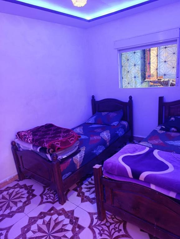 two beds in a room with purple sheets at Casa Yessef Akchour in Akchour