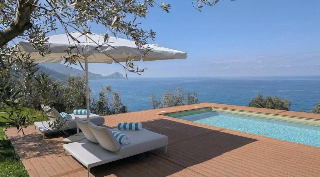 a swimming pool with an umbrella and chairs next to it at Villa Torre Conca Cefalu Coast in Finale