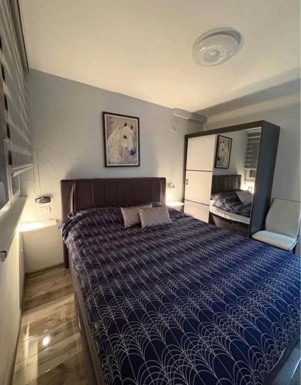a bedroom with a large bed with a blue comforter at Jadranka in Vinkovci