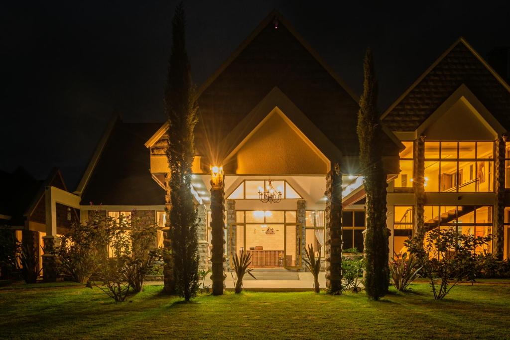 a house at night with palm trees in front at WOODSY Resort in Nanyuki