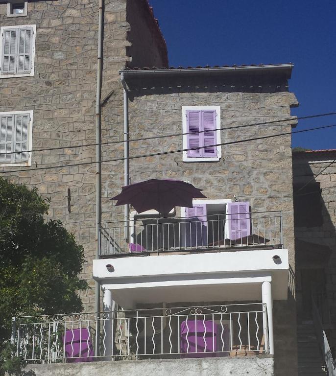 a balcony with an umbrella on top of a building at Studio de la maison Lilas in Pila-Canale