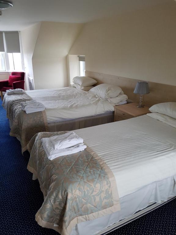 a hotel room with three beds in a room at Aboukir Hotel in Panbride