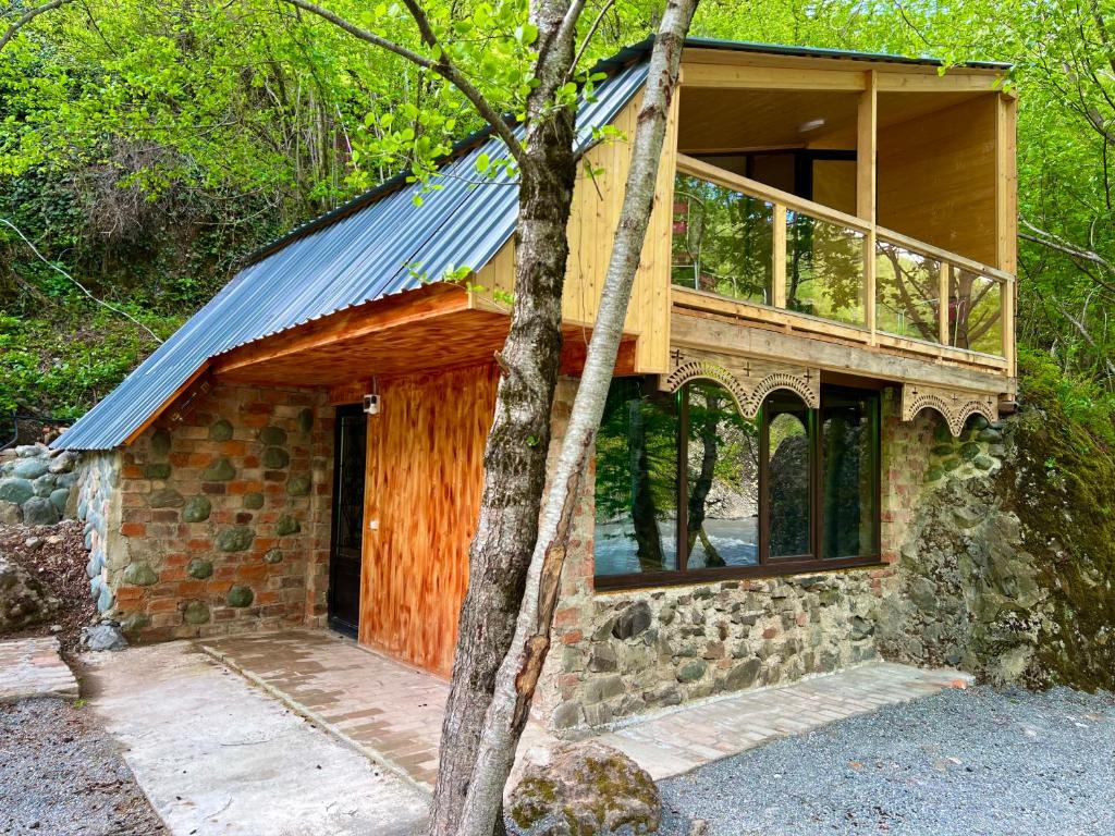 a stone house with a balcony and a tree at kirke in Tsesi