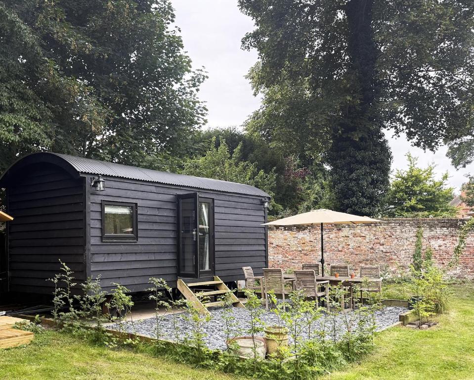 a black tiny house with chairs and an umbrella at Orchard House Holiday in Bungay