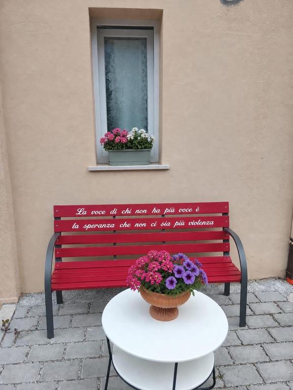a red bench with a table and a window at Le stanze di veneranda in Silvi Marina