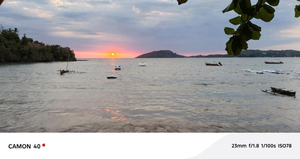 a picture of a sunset on the water with boats at Piscine bimoko in Nosy Be