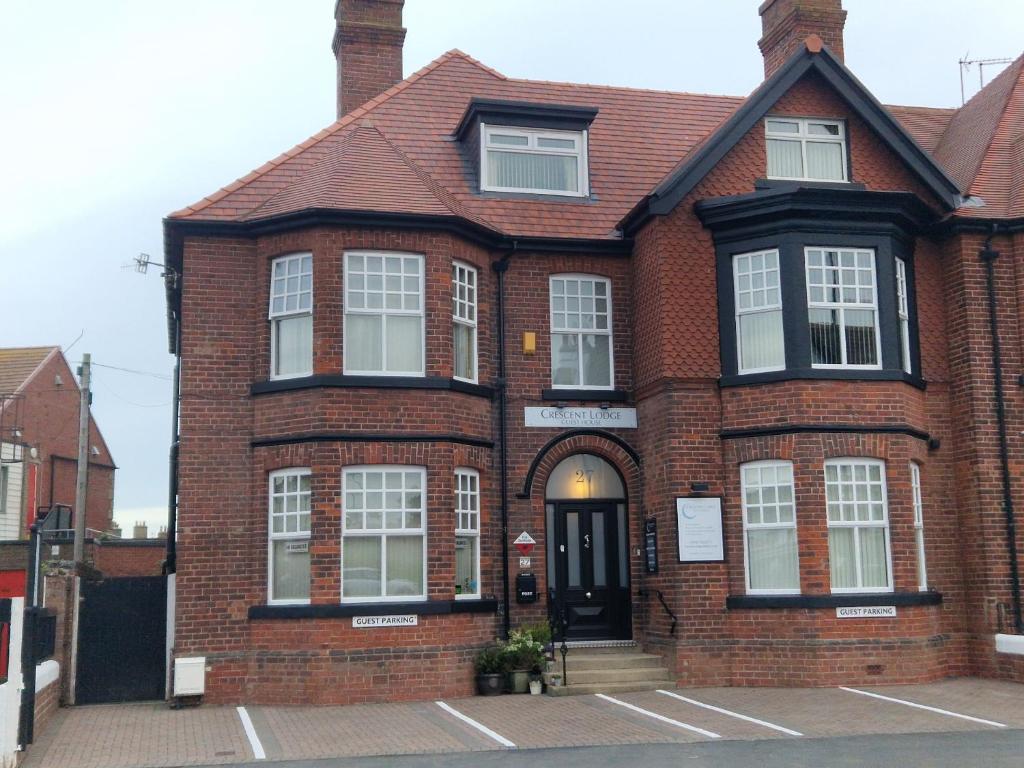 a red brick house with a black door at Crescent Lodge Guest House in Whitby