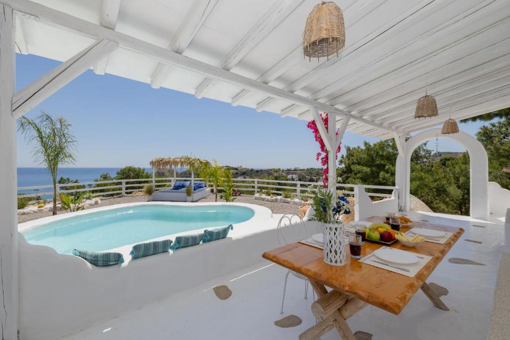 a villa with a swimming pool and a table at Endless Horizon At Stegna in Archangelos