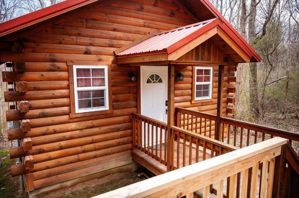 a log cabin with a porch and a white door at Buckeye Bungalow in Logan