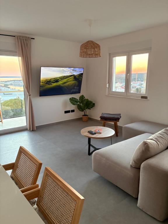 a living room with a couch and a tv on the wall at Maris Loft Šimuni in Šimuni