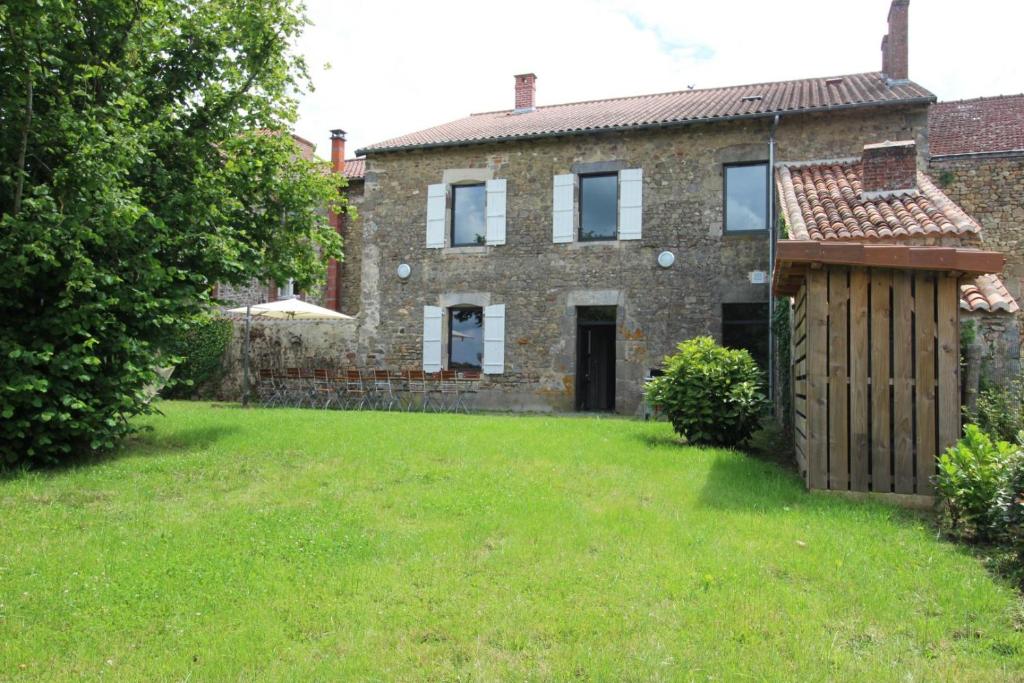 an old brick house with a green yard at Le presbytère de thiat in Thiat
