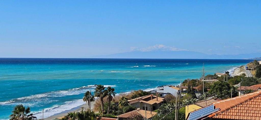 a view of the ocean and a beach with palm trees at RaJan Home Blue in Palizzi Marina